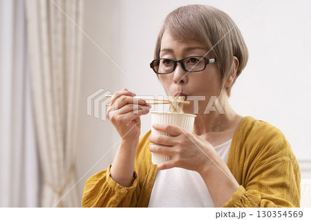 ダイニングでインスタント麺を食べるシニア女性 ダイニングでインスタント麺を食べるシニア女性 130354569