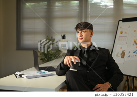 Entrepreneur in formal attire holding coffee and looking away thoughtfully Entrepreneur in formal attire holding coffee and looking away thoughtfully 130355421