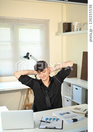 Relaxed office worker taking a break after working on financial reports 130355536