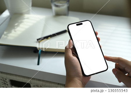 Close up of person holding smartphone with blank screen, finger pointing at display Close up of person holding smartphone with blank screen, finger pointing at display 130355543