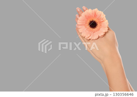 Hand gently cradles a pink flower while promoting body care 130356646