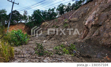 A rocky cliff with landslide debris, fallen trees, and mud after heavy rain, showing the impact of natural disaster and erosion. 130357104
