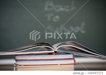 Open book on top of a stack of books with a chalkboard background. Open book on top of a stack of books with a chalkboard background. 130357171