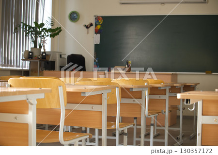The classroom is set for learning with neatly arranged desks and a chalkboard. The classroom is set for learning with neatly arranged desks and a chalkboard. 130357172