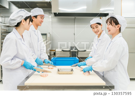 鶏肉を調理するコックコート姿の男女スタッフ(調理師・料理人・生鮮市場・食品加工) 鶏肉を調理するコックコート姿の男女スタッフ(調理師・料理人・生鮮市場・食品加工) 130357595