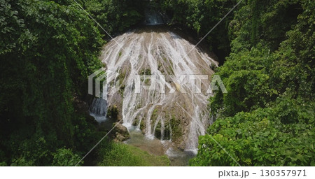 Fiji, Port Villa: Aerial drone of stunning cascade waterfall flowing through a vibrant tropical green rainforest on Efate Island. Vanuatu. Wild nature landscape, travel background. 130357971