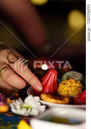 Hand reaching for traditional sweets during Diwali festivities 130358853