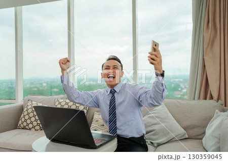 An excited businessman is celebrating his success in a modern home office setting 130359045