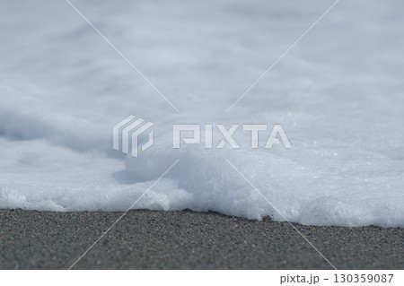 砂浜に寄せた波の先端の泡 130359087