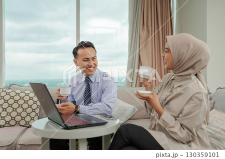 Young Professionals Engaged in Conversation with Laptop at Modern Office 130359101