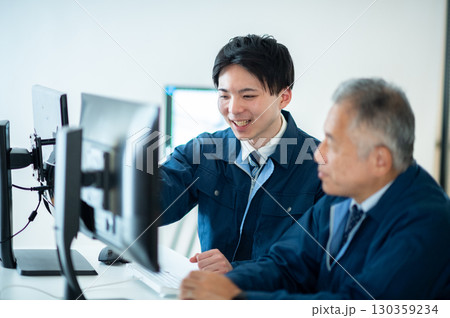 オフィスで会話するベテランと若手 130359234