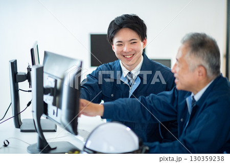 オフィスで会話するベテランと若手 130359238