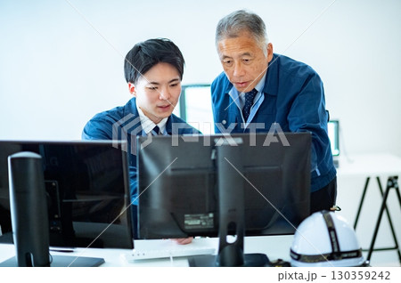 オフィスで会話するベテランと若手 130359242