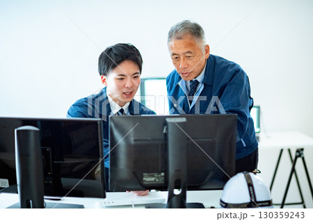 オフィスで会話するベテランと若手 130359243