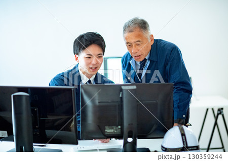 オフィスで会話するベテランと若手 130359244