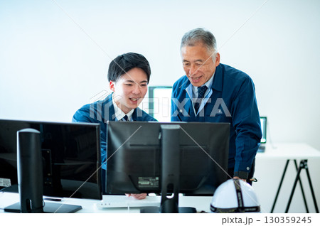 オフィスで会話するベテランと若手 130359245