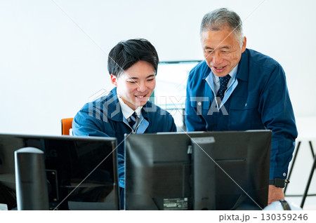 オフィスで会話するベテランと若手 130359246