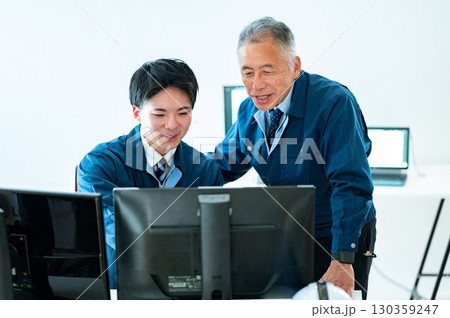 オフィスで会話するベテランと若手 130359247
