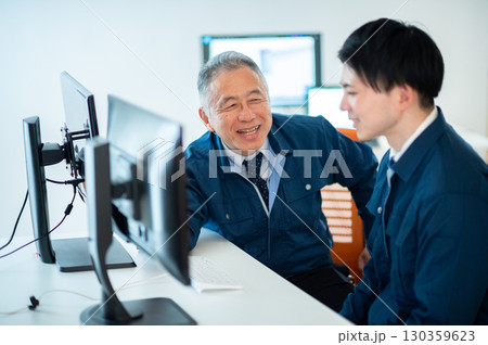 オフィスで会話するベテランと若手 130359623