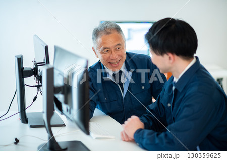 オフィスで会話するベテランと若手 オフィスで会話するベテランと若手 130359625