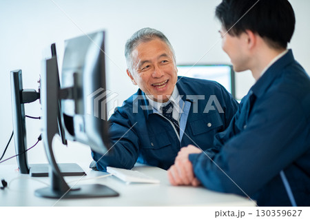 オフィスで会話するベテランと若手 130359627