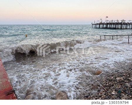 The sea reflects soft evening light under cloudy sky with distant horizon line. Calm waves, marine ecology and coastal landscape in seasonal outdoor environment. 130359794