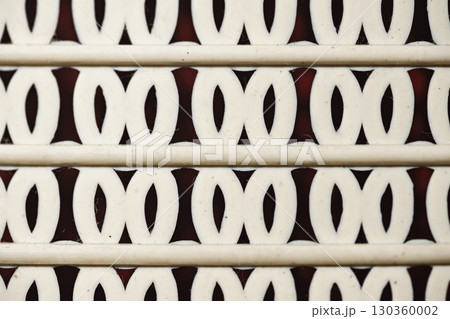 Closeup detail of a horizontal pattern comprised of parallel lines interspersed with repeating oval shapes against a contrasting dark background. Geometric textures background Closeup detail of a horizontal pattern comprised of parallel lines interspersed with repeating oval shapes against a contrasting dark background. Geometric textures background 130360002