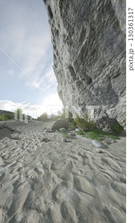 A large rock rests on the sandy beach, contrasting against the smooth texture of the sand. A large rock rests on the sandy beach, contrasting against the smooth texture of the sand. 130361317