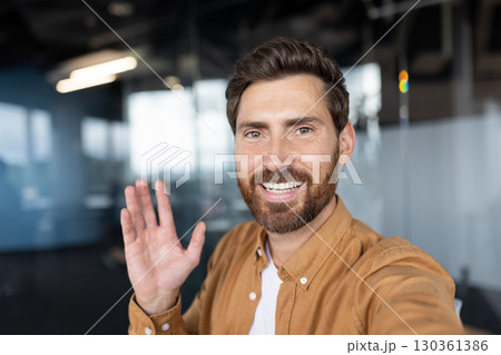 Friendly professional greeting casually in office setting, likely during virtual meeting or conversation. 130361386