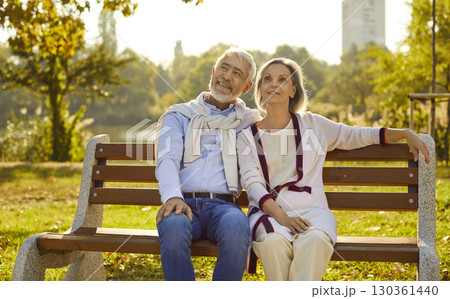 Happy senior couple sitting on the bench in park enjoying retirement in nature. 130361440