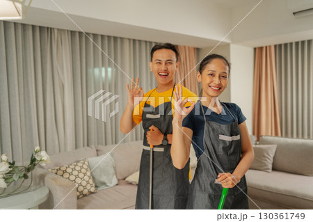 Happy Cleaning Professionals are Smiling and Giving Thumbs Up in a Modern Living Room Happy Cleaning Professionals are Smiling and Giving Thumbs Up in a Modern Living Room 130361749