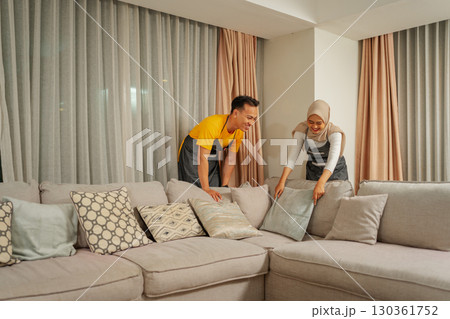 A Couple Silently Rearranging Cushions on a Cozy Sofa in Modern Living Room A Couple Silently Rearranging Cushions on a Cozy Sofa in Modern Living Room 130361752