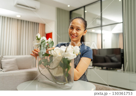 A Cheerful Woman Arranging Beautiful White Flowers in a Modern Living Room A Cheerful Woman Arranging Beautiful White Flowers in a Modern Living Room 130361753