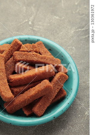 Tasty rye croutons on plate on grey concrete background. Vertical photo 130361972
