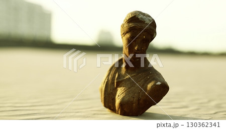 A serene bronze sculpture stands on golden sands, gently illuminated by the warm evening light. The tranquil setting invites contemplation, blending art and nature beautifully. A serene bronze sculpture stands on golden sands, gently illuminated by the warm evening light. The tranquil setting invites contemplation, blending art and nature beautifully. 130362341