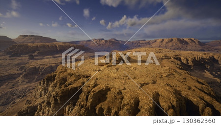 A breathtaking desert expanse reveals majestic rock formations bathed in golden sunlight. The distant mountains and fluffy clouds create a picturesque canvas, inviting adventure and exploration. A breathtaking desert expanse reveals majestic rock formations bathed in golden sunlight. The distant mountains and fluffy clouds create a picturesque canvas, inviting adventure and exploration. 130362360