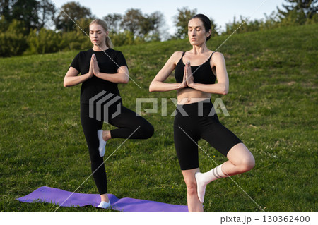 Practicing yoga in the park during a sunny afternoon with friends 130362400