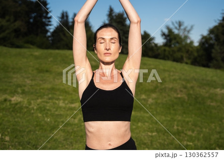 Woman practicing yoga outdoors under a clear blue sky during daytime Woman practicing yoga outdoors under a clear blue sky during daytime 130362557