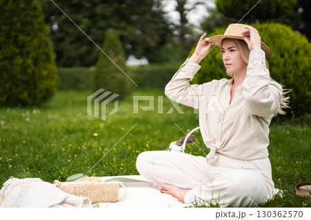 Woman enjoying a peaceful picnic on a sunny day in a lush green park Woman enjoying a peaceful picnic on a sunny day in a lush green park 130362570