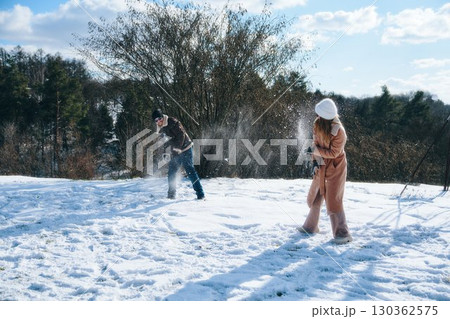 Fun winter day as friends play in fresh snow near trees 130362575