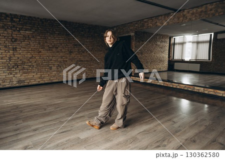 Young dancer practicing movement in an empty studio with wooden floors 130362580