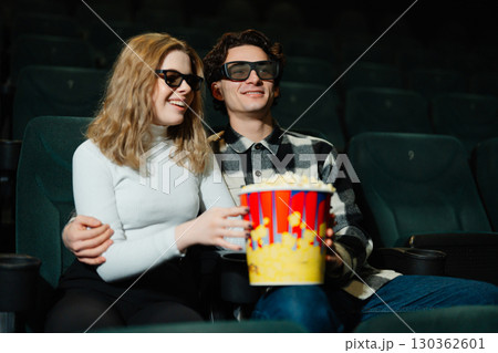 Couple enjoying a movie together in a theater with popcorn 130362601