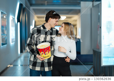 Young couple enjoys a fun outing at the cinema with popcorn in hand Young couple enjoys a fun outing at the cinema with popcorn in hand 130362636