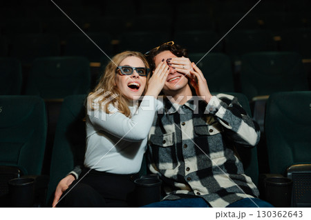 Excited couple enjoying a movie together in a theater seat Excited couple enjoying a movie together in a theater seat 130362643