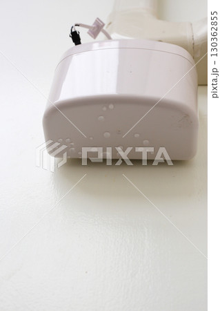 Wall-mounted drain pump for air conditioner with water droplets underneath, indicating malfunction or leakage. Wall-mounted drain pump for air conditioner with water droplets underneath, indicating malfunction or leakage. 130362855