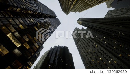 Skyline is filled with towering skyscrapers reflecting city lights as dusk sets in. The interplay of architecture and the grey sky creates a dramatic urban atmosphere rich in energy. Skyline is filled with towering skyscrapers reflecting city lights as dusk sets in. The interplay of architecture and the grey sky creates a dramatic urban atmosphere rich in energy. 130362920