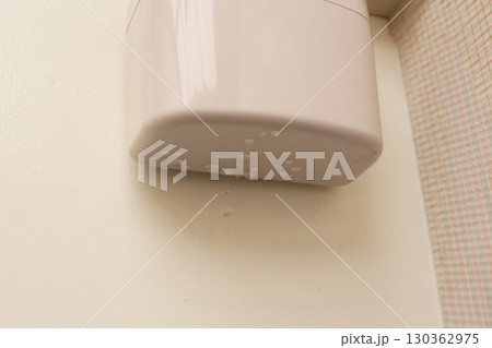 Wall-mounted drain pump for air conditioner with water droplets underneath, indicating malfunction or leakage. Wall-mounted drain pump for air conditioner with water droplets underneath, indicating malfunction or leakage. 130362975