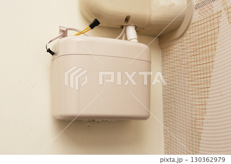 Wall-mounted drain pump for air conditioner with water droplets underneath, indicating malfunction or leakage. 130362979