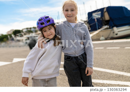Playful girls wearing standing near marina with yachts Playful girls wearing standing near marina with yachts 130363294