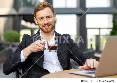 Caucasian professional checking emails on laptop with coffee 130363389
